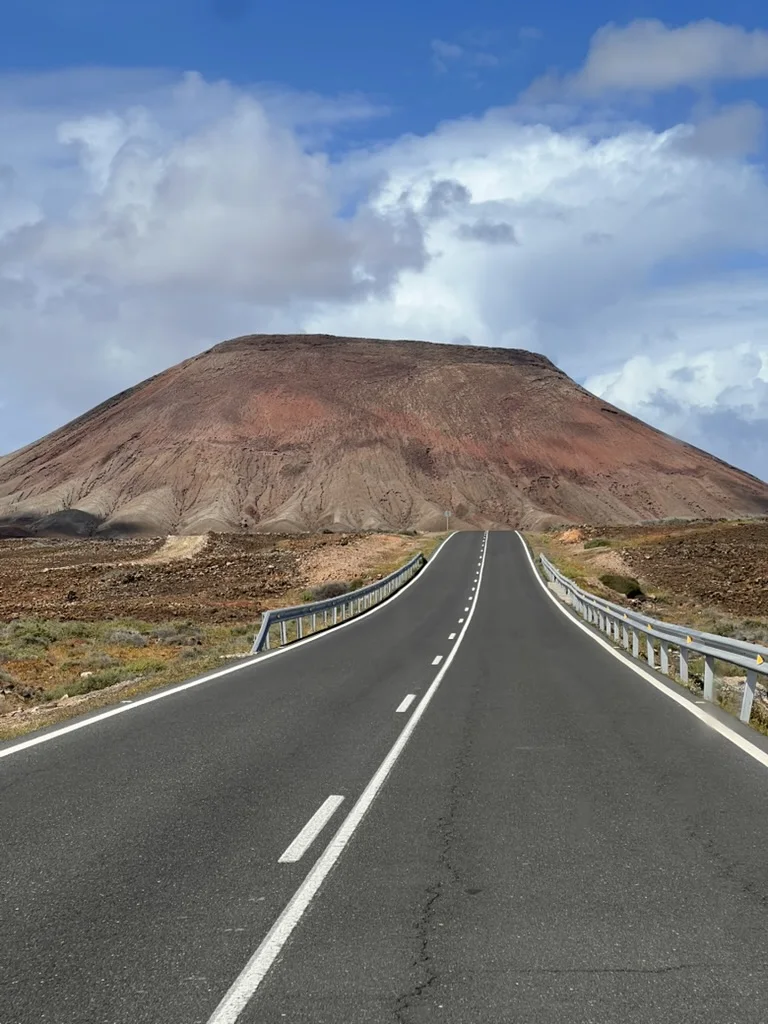 A straight empty road leading to a red volcano